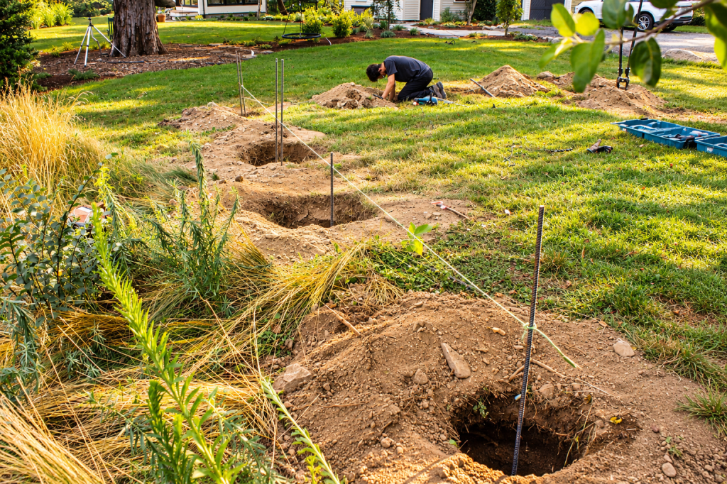 JMJ Gardens crew preparing a residential yard with measured post holes, layout lines, and site work for a custom outdoor construction project.