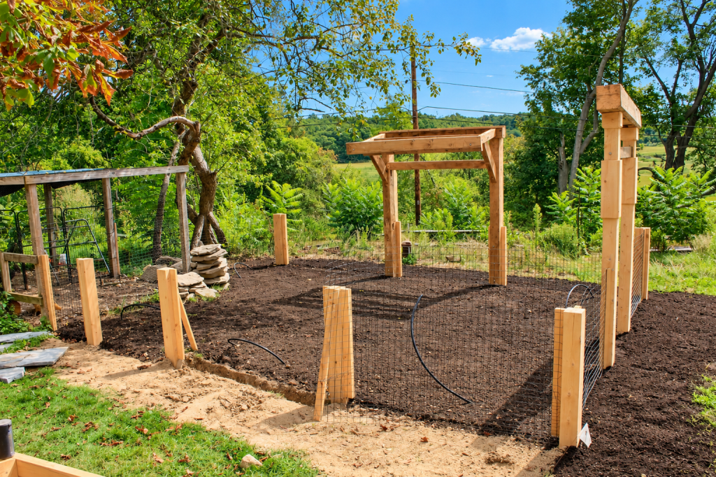 Custom timber garden arbor and wire fencing installation by JMJ Gardens, surrounded by mature trees and natural landscaping.